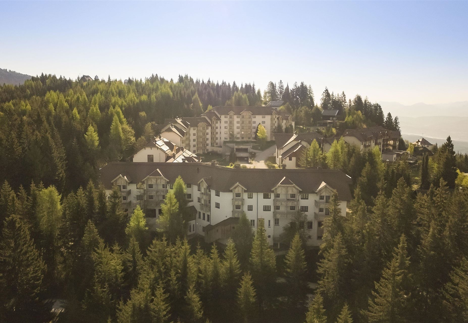 Un resort pittoresco, circondato da foreste dense e montagne. Gli edifici sono armoniosamente integrati nell'ambiente naturale.
