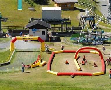 Ein Familienfreizeitpark mit einer kleinen Rennbahn aus aufblasbaren Elementen. Viele Kinder haben Spaß beim Fahren mit kleinen Fahrzeugen.