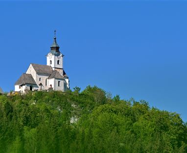 Eine malerische Kirche steht auf einem grünen Hügel. Der blaue Himmel bildet einen schönen Kontrast zur Landschaft.
