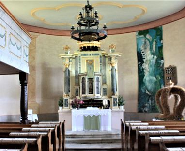 Eine schöne Kirche mit einem festlichen Altar und Holzbänken. Sanfte Farben und Licht strömen durch die Fenster.