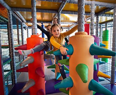 Ein bunter Indoorspielplatz mit verschiedenen Klettergeräten. Kinder spielen und haben Spaß in der Spielstruktur.