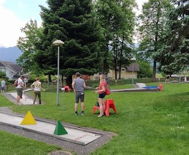 Ein Mini-Golfplatz in einem grünen Park. Menschen spielen Golf und genießen die frische Luft.