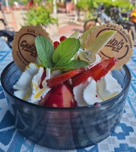 A delicious dessert with fresh strawberries, cream, and a hint of mint. The dish is decorated with crunchy cookies and colorful fruits.