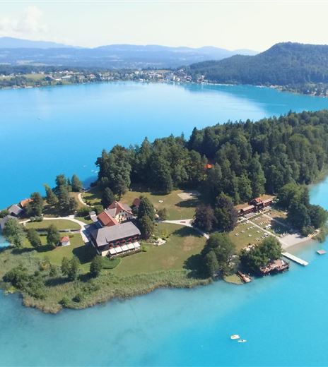 Un'isola pittoresca in un chiaro lago blu.  
Circondata da alberi e prati, il paesaggio emana tranquillità e bellezza.