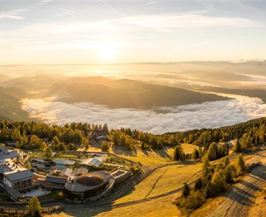 Eine malerische Landschaft mit Sonnenaufgang über den Bergen. Sanfte Hügel und Nebel bedecken das Tal.