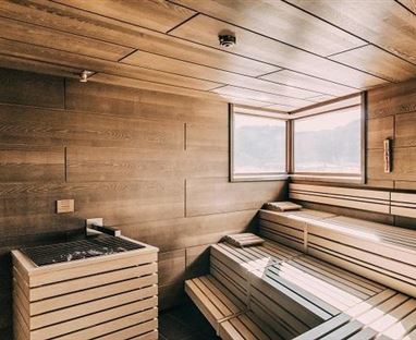 Eine moderne Sauna mit Holzrelief und großen Fenstern. Der Raum ist hell und einladend gestaltet.