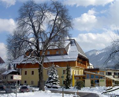 Un bel hotel in un paesaggio innevato. Sullo sfondo ci sono montagne e un cielo blu.