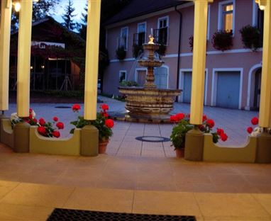 Ein schöner Innenhof mit einem Brunnen in der Mitte. Blumen in Töpfen und eine sanfte Beleuchtung schaffen eine einladende Atmosphäre.