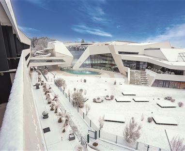 Eine moderne Architektur im Winter, umgeben von Schnee. Der Himmel ist klar und blau, und die Anlage ist elegant gestaltet.