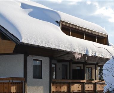Ein Gebäude im Schnee mit einem schneebedeckten Dach. Eiszapfen hängen von der Überdachung.
