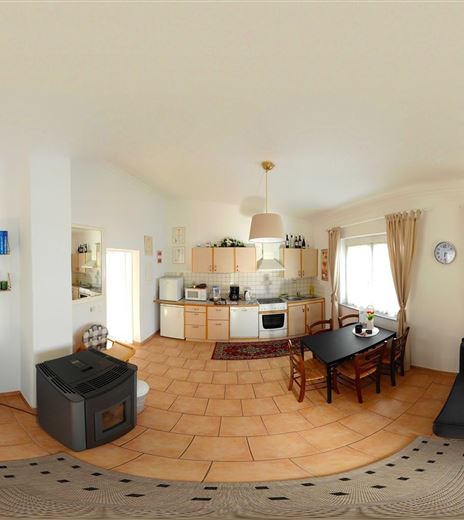 Ein helles, modernes Wohn- und Esszimmer mit einer offenen Küche. Es gibt gemütliche Möbel und große Fenster, die viel Licht hereinlassen.