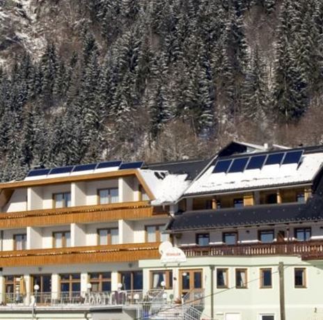A cozy hotel in the mountains, surrounded by snow-covered fir trees. The sky is clear and the landscape radiates tranquility.
