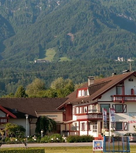 A picturesque house in a mountainous landscape. In the background, green hills and trees can be seen.