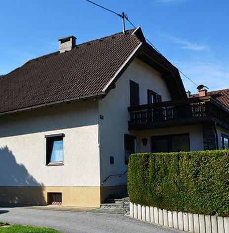 Ein einfamilienhaus mit einem zuletzt renovierten äußeren Erscheinungsbild. Es steht in einer ruhigen Wohngegend, umgeben von Hecken und Bäumen.