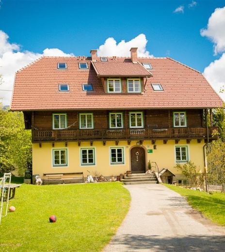 Ein charmantes, dreigeschossiges Haus mit rotem Dach und gelber Fassade. Der Garten ist grün und einladend, ideal für Freizeitaktivitäten.