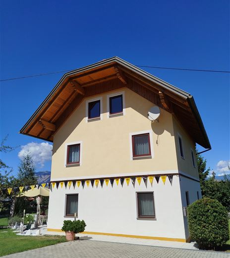 Una bella casa con un tetto a due falde e facciata gialla. Nastri svolazzanti decorano la parte anteriore.