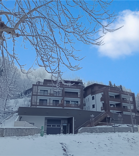 Ein modernes Gebäude in einer verschneiten Landschaft. Der Himmel ist klar und blau, umgeben von schneebedeckten Bäumen.