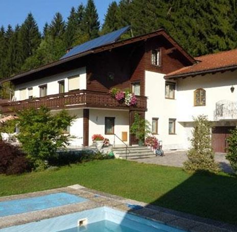 Una bella casa nel verde con una piscina davanti. Circondata da alberi e piante fiorite, offre un'atmosfera rilassante.