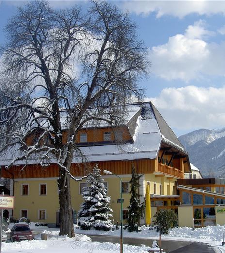 A beautiful hotel in a snow-covered landscape. In the background are mountains and a blue sky.