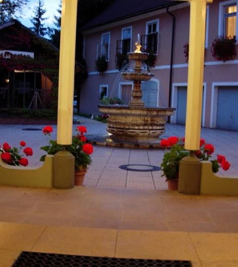A beautiful courtyard with a fountain in the center. Flowers in pots and gentle lighting create an inviting atmosphere.