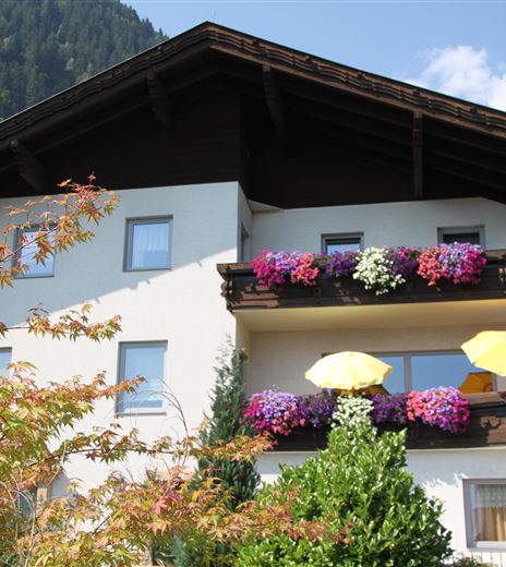 Una bella casa con balconi decorati con fiori colorati. Ombrelloni gialli offrono una vista accogliente sull'ambiente.