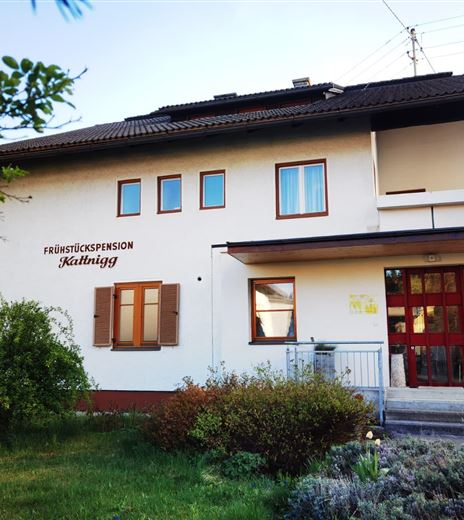 Ein gemütliches Frühstückspension Gebäude mit einem einladenden Eingang. Umgeben von Grünflächen und Sträuchern.