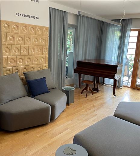 Un soggiorno elegante con mobili moderni e un pianoforte.  
Grandi finestre garantiscono molta luce diurna e un'atmosfera accogliente.