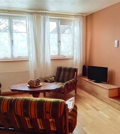 Una comoda soggiorno con due divani e un tavolo. Finestre luminose lasciano entrare molta luce e sullo sfondo si vede una zona pranzo.